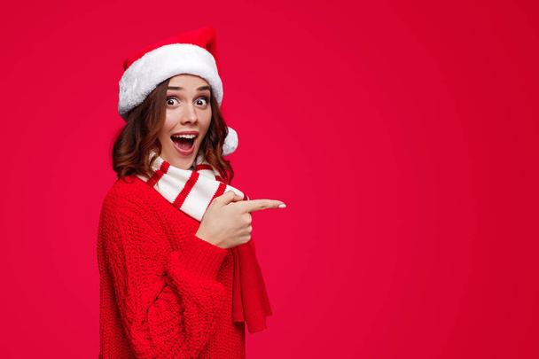 Excited woman in Christmas hat pointing aside - Φωτογραφία, εικόνα