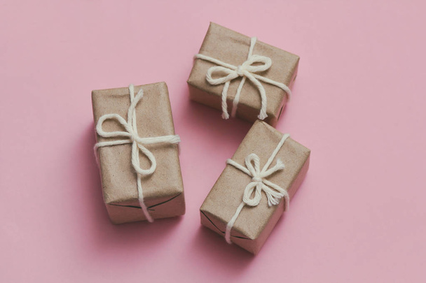 Set of parcels wrapping in brown craft paper and tie hemp string. Package. Delivery service. Online shopping. Your purchase. Gift box on a table. Pink solid background. - Photo, Image