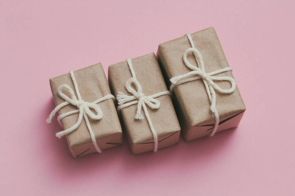 Set of parcels wrapping in brown craft paper and tie hemp string. Package. Delivery service. Online shopping. Your purchase. Gift box on a table. Pink solid background. - Photo, Image