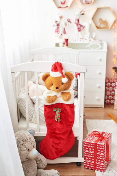 Guardería de Navidad, decoración de Navidad en el dormitorio de los niños, sala de juegos para niños decorada para el año nuevo, dormitorio de los niños blancos, juguetes de Navidad y regalos en el dormitorio de los niños, cama blanca con juguetes suaves
 - Foto, Imagen