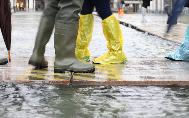 emberek gumicsizmával és műanyag lábszárvédővel Velencében Olaszország - Fotó, kép