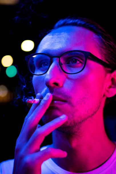 Ročník, červený a modrý portrét mladého muže, jak kouří cigaretu - Fotografie, Obrázek