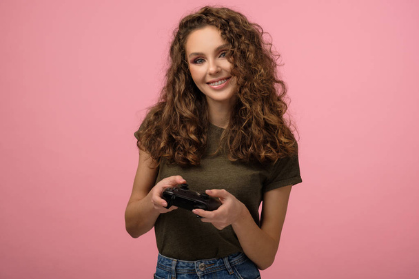 Pretty geek girl with gamepad on pink background - Foto, imagen