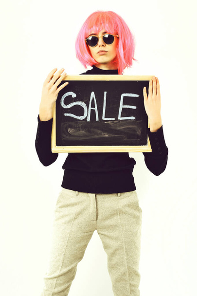 fashionable girl in wig holding board with sale inscription - Fotografie, Obrázek
