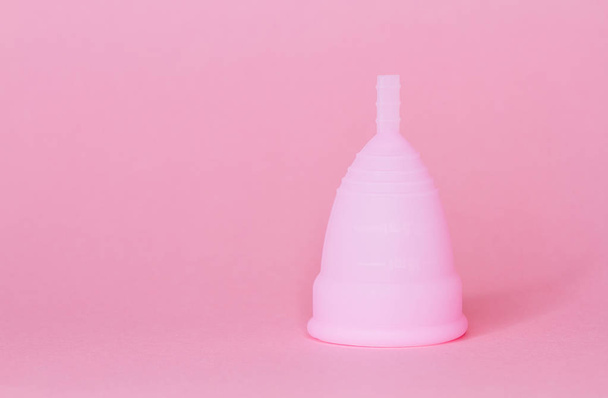 woman hands holding reusable pink silicone menstrual cup on pink background - Foto, Bild
