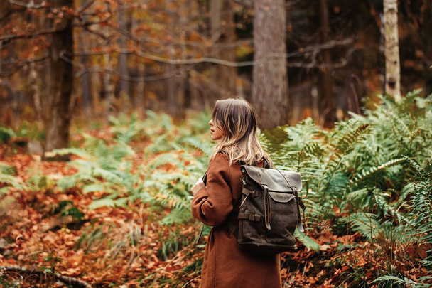 girl with a backpack in the autumn forest - Фото, зображення