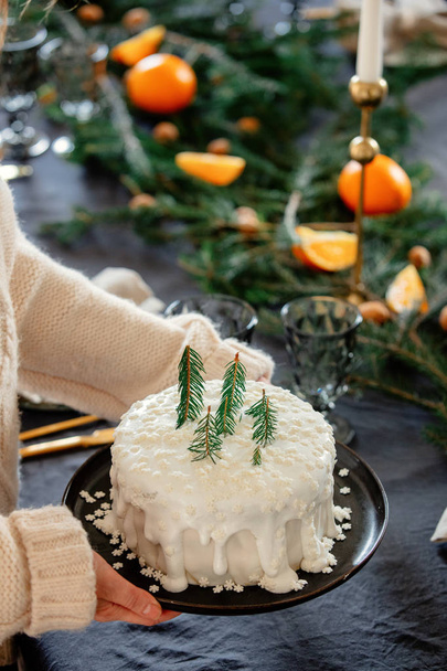 Γυναίκα κρατώντας χριστουγεννιάτικο κέικ με κρέμα πάνω από ένα τραπέζι - Φωτογραφία, εικόνα