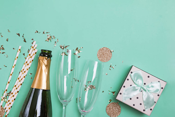 Bottle of a champagne, gift box, golden confetti and glasses. - Фото, изображение