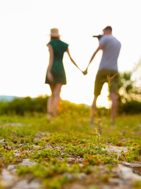 Unfocused silhouettes of man and woman having fun and taking pictures outdoors at sunset. - 写真・画像