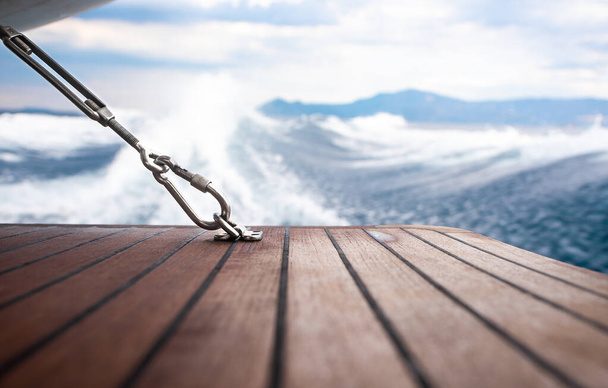 Close up stainless steel carabiner attached to wooden floor of yacht. - Photo, Image