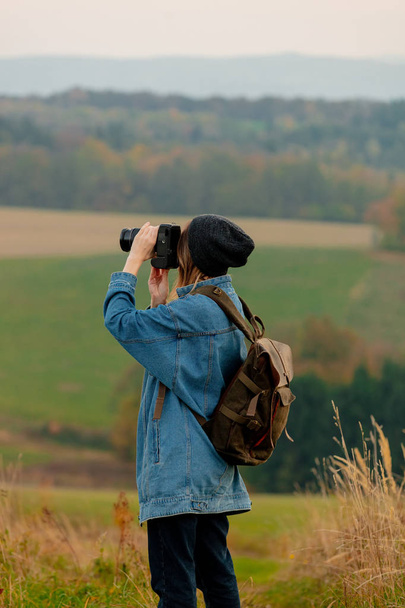 Style girl with camera and backpack at countryside with mountain - Fotó, kép