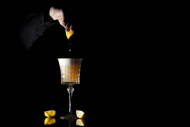 Barkeeper macht klassischen Bernstein-Cocktail mit Zitrusfrüchten und Eis auf schwarzem Hintergrund - Foto, Bild