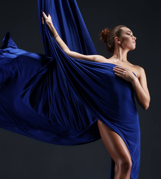 Slim girl wrapped in blue aerial silks - Foto, afbeelding