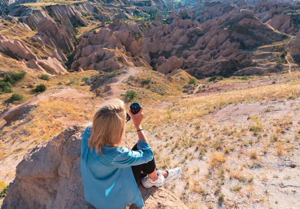 Nainen tumbler kuppi kahvia istuu kukkulalla nauttia maisemista
. - Valokuva, kuva