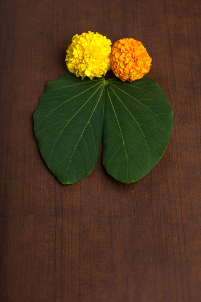 インドの祭りデュッセラは、茶色の背景に金色の葉(Bauhinia racemosa)とマリーゴールドの花を示しています. - 写真・画像