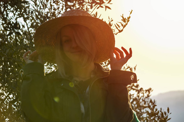 Young woman with straw hat smiling to camera. Sunset on background. Fun time travel concept. - Foto, imagen