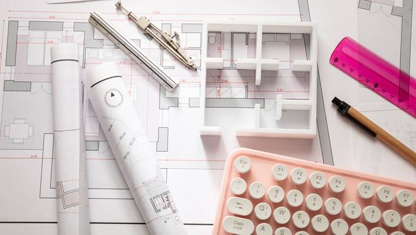 Concepto de construcción. Dibujos planos de edificios residenciales y un teclado rosa para computadora
 - Foto, imagen