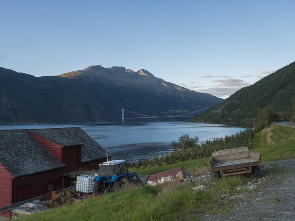 Uitzicht op Hardanger Bridge over fjord Hardangerfjorden verbindt Ullensvang met Ulvikin, Noorwegen. Langste tunnel naar tunnel hangbrug ter wereld 1380 meter. Zomer dag gouden uur. - Foto, afbeelding