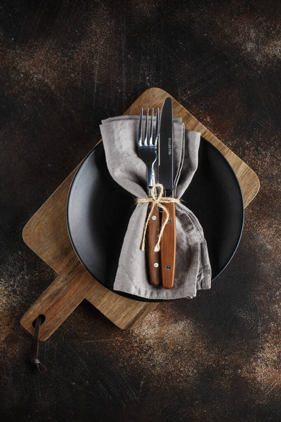 Cutlery on the plate on dark brown background.  - Фото, изображение