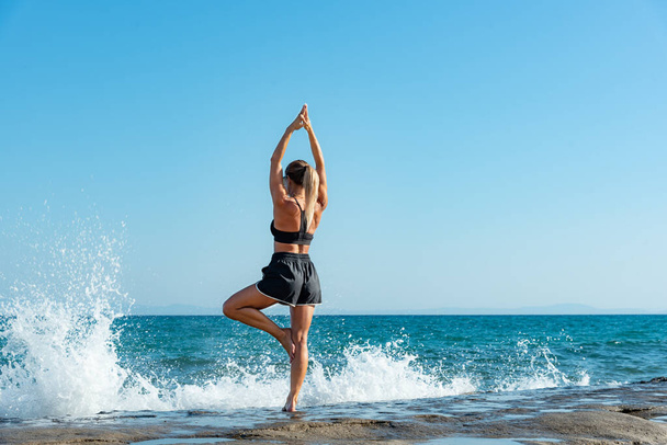 Young blonde woman doing morning exercises by the beach - Φωτογραφία, εικόνα