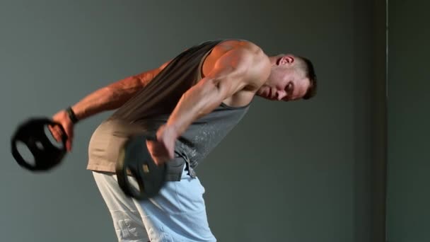 Молодий атлетичний чоловік займається фізичними вправами у спортзалі. Плечі піднімаються з тарілками
 - Кадри, відео