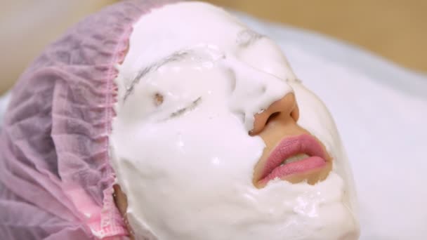 Jeune femme dans un salon de beauté fait masque d'alginate. Application d'hydratant, adoucissant, masque régénérant avant le rajeunissement, tonifiant darsonval procédure sur le visage. Matériel de beauté médicale
. - Séquence, vidéo