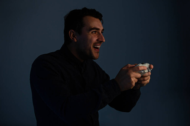 fröhlicher junger Mann spielt Videospiele isoliert auf grauem Hintergrund - Foto, Bild