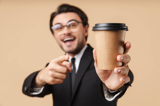 Image of positive businessman pointing finger and holding coffee - Photo, Image