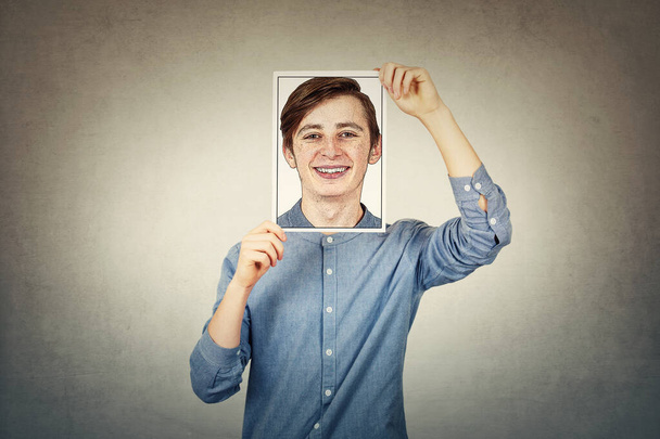 Adolescente niño cubriendo la cara usando un papel foto impresión con uno mismo po
 - Foto, Imagen