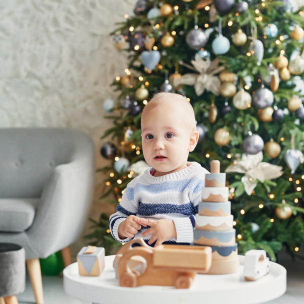Cute little boy is playing with toy wooden train, toy car, pyramid and cubes, learning development concept. Development of kids fine motor skills, imagination and logical thinking - Photo, image