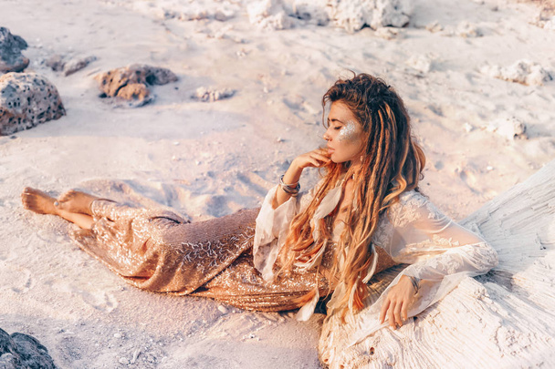 beautiful young woman in elegant dress lying on sand  - Photo, image