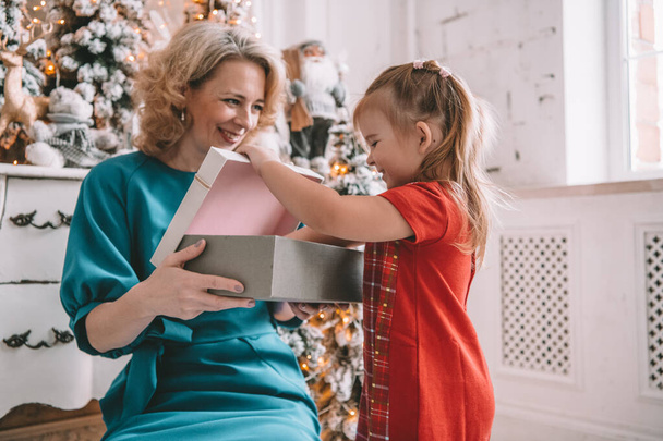 Surprise christmas present - little girl and woman in front of the decorated tree - Фото, зображення