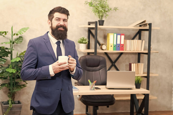 Start day with coffee. Coffee relaxing break. Boss enjoying energy drink. Caffeine addicted. Man bearded businessman hold cup stand office. Successful people drink coffee. Coffee is always good idea - Foto, imagen
