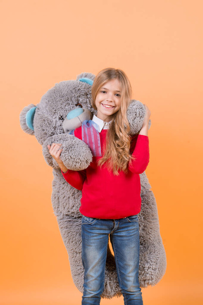 Girl hug big teddy bear on orange background - Zdjęcie, obraz