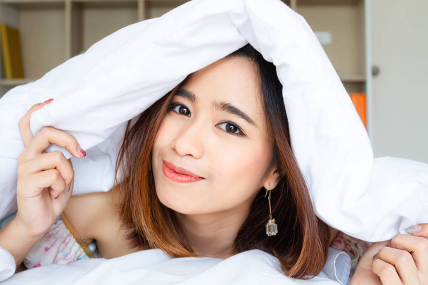 Close up portrait pretty young woman under white blanket  - 写真・画像