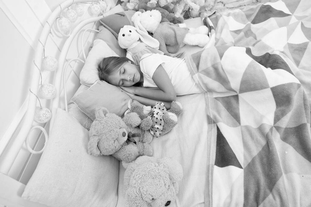 New Year is coming. Cute girl fell asleep after Christmas night. Sleeping child. Little child sleep at Christmas tree. Little girl lying in bed with toys. Peaceful sleep and rest on winter holidays - Фото, изображение