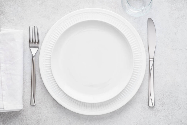 Table setting with white plates, glass, napkin, fork and knife. - Foto, afbeelding