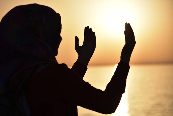 Silhueta de uma mulher muçulmana rezando durante o pôr do sol no grande sh
 - Foto, Imagem