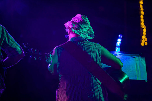 Nainen soittaa kitaristia lavalla
  - Valokuva, kuva