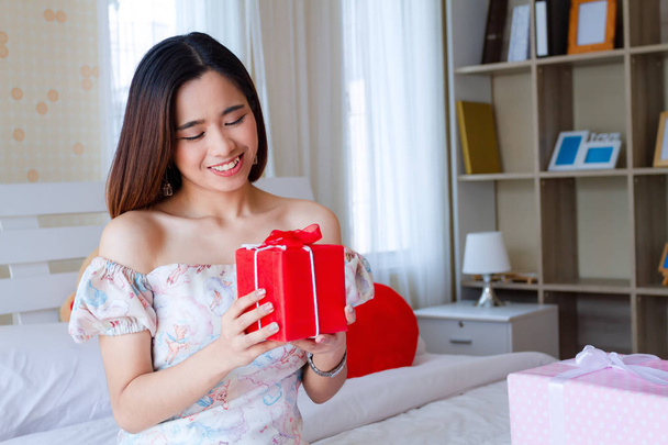 Young woman happy with red present in bedroom - Photo, Image