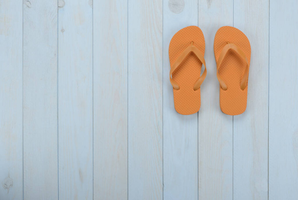 Freizeitartikel auf blauem Holzhintergrund: orangefarbene Flip-Flops - Foto, Bild
