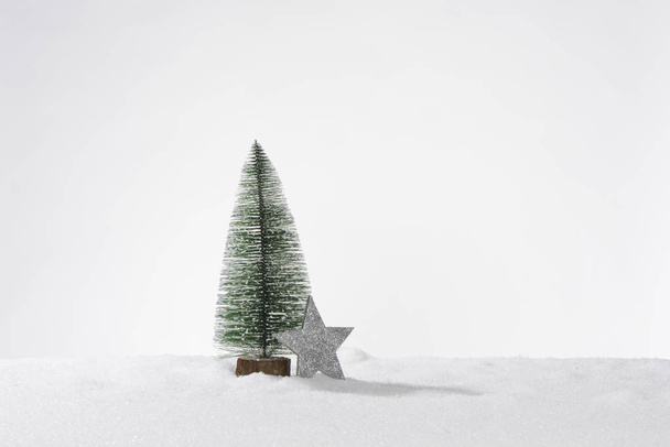 Koristeellinen keinotekoinen joulukuusi keinotekoinen lumi ja yksi harmaa tähti, koostumus korttina tai bannerina
 - Valokuva, kuva