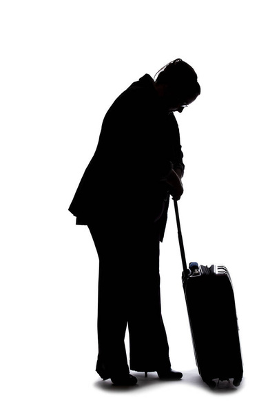 Silhouette of a businesswoman going on a business trip and traveling with luggage.  She is carrying bags like preparing to board a flight at an airport.  - Фото, изображение