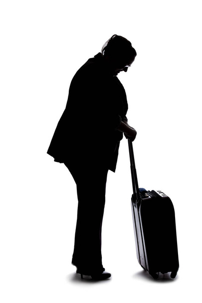 Silhouette of a businesswoman going on a business trip and traveling with luggage.  She is carrying bags like preparing to board a flight at an airport.  - Fotó, kép