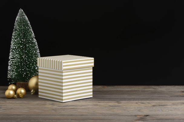 Box of golden and white stripes on wooden and black background - Zdjęcie, obraz
