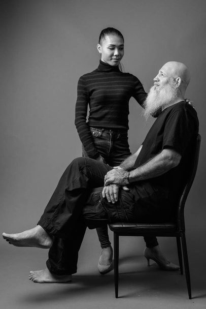 Mature bearded bald man with young Asian transgender woman together in black and white - Photo, Image