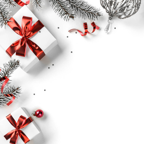 Рождественские елки, подарочные коробки с красной лентой, красные украшения, блеск и конфетти на белом фоне. Рождественские и новогодние открытки, зимние праздники. Плоский, вид сверху - Фото, изображение