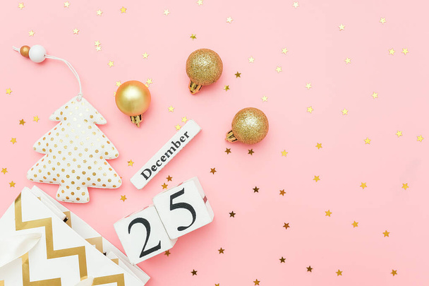 Wooden calendar December 25, textile christmas tree, golden baubles, stars confetti on pink background. Merry christmas concept. Top view Flat lay Template for design, greeting card, postcard - Φωτογραφία, εικόνα