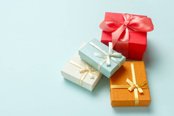 Small gift boxes are stacked on a pastel turquoise background. Christmas presents. - Foto, afbeelding