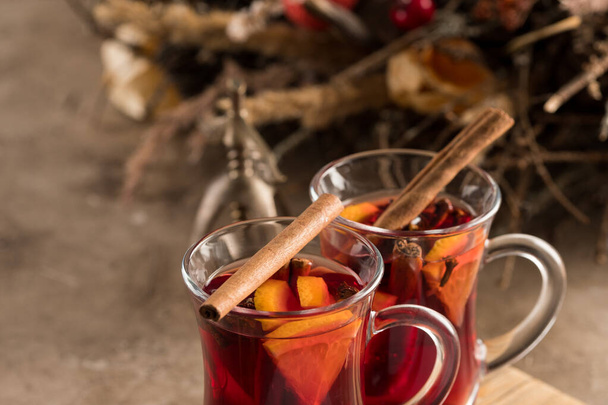 Two glasses of christmas mulled wine with oranges and spices on a textural background. Selective focus. Copy space. - 写真・画像